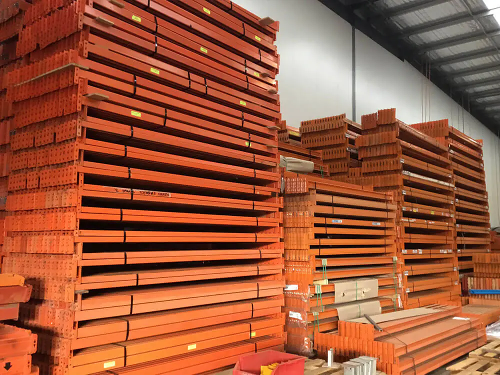 Orange pallet racking beams organized by size in warehouse inventory