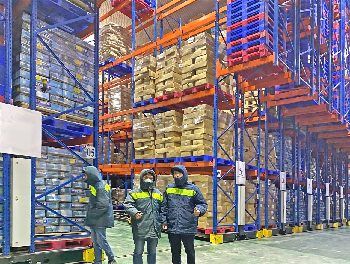 Warehouse personnel inspecting loaded pallet racking in a cold-storage facility