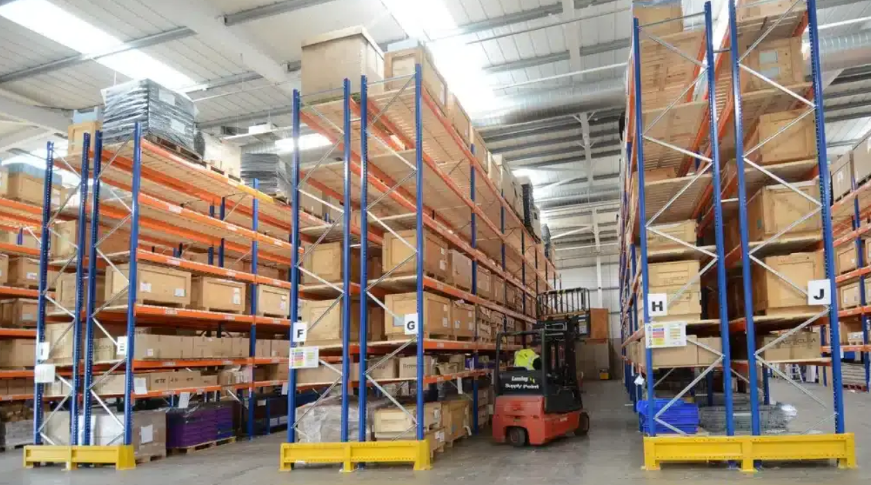 Forklift lifting a pallet beside warehouse racks designed for pallet dimensions