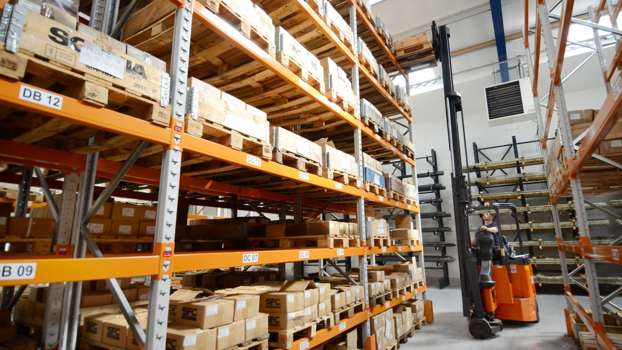Warehouse pallet racks stocked with boxed goods for forklift aisle access